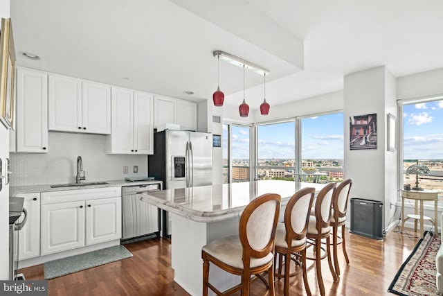 kitchen featuring appliances with stainless steel finishes, backsplash, sink, decorative light fixtures, and white cabinets