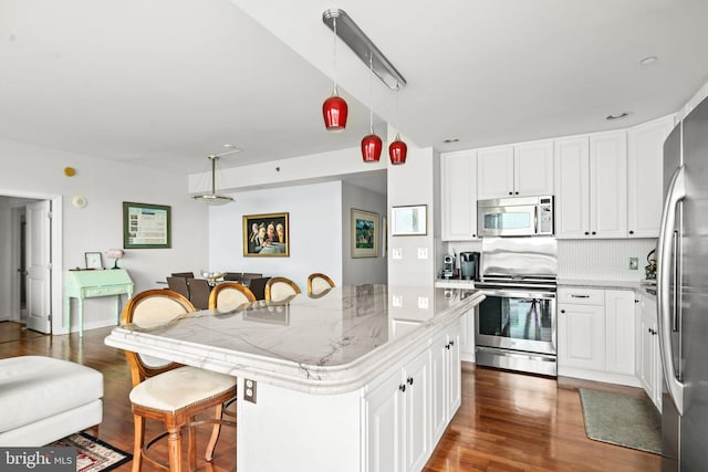 kitchen with white cabinetry, a center island, hanging light fixtures, stainless steel appliances, and tasteful backsplash