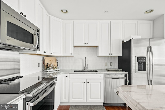 kitchen with white cabinets, decorative backsplash, sink, and appliances with stainless steel finishes