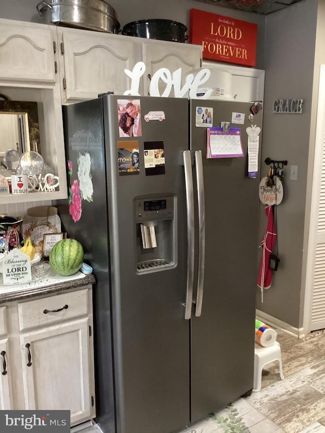 kitchen with stainless steel fridge, light wood-type flooring, and white cabinetry