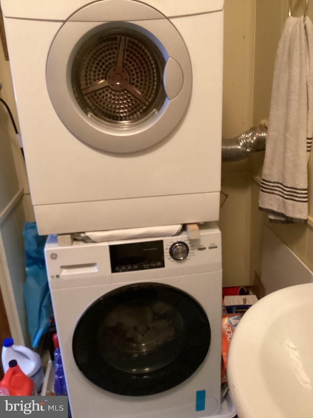 clothes washing area with sink and stacked washer / drying machine