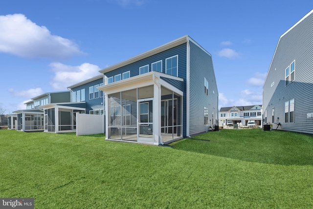 rear view of property featuring a yard and a sunroom