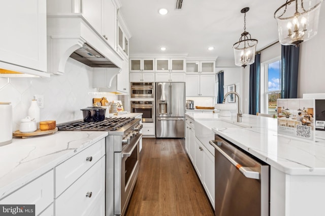 kitchen featuring high end appliances, light stone countertops, pendant lighting, white cabinetry, and dark hardwood / wood-style floors