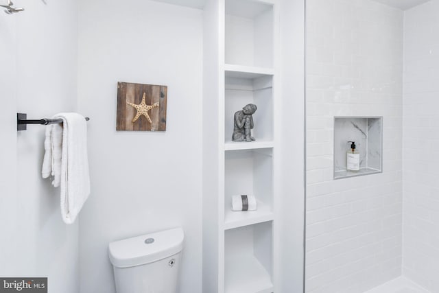 bathroom with built in features, a shower, and toilet