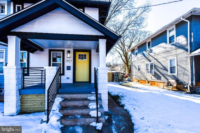 snow covered property entrance featuring a porch