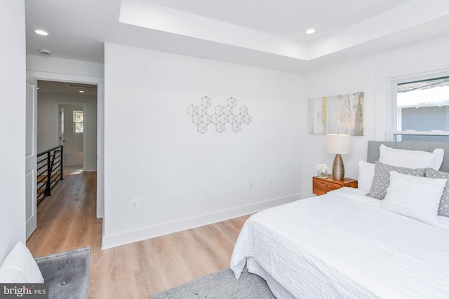 bedroom featuring a raised ceiling and light hardwood / wood-style floors