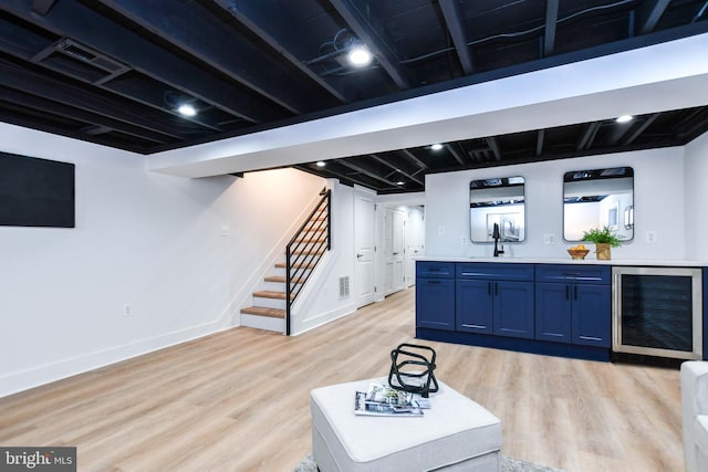 basement with wine cooler, light hardwood / wood-style flooring, and sink