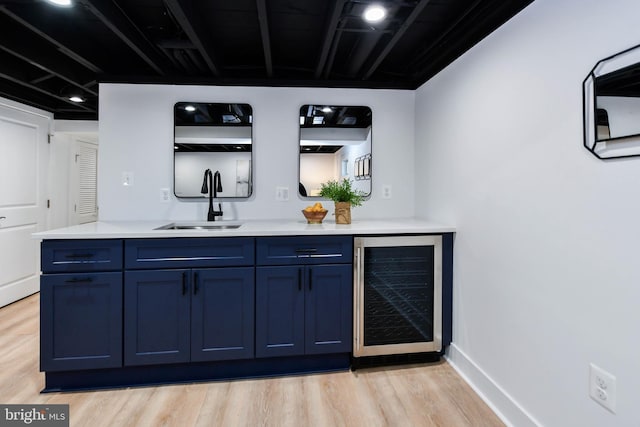 bar with sink, light hardwood / wood-style flooring, beverage cooler, and blue cabinets