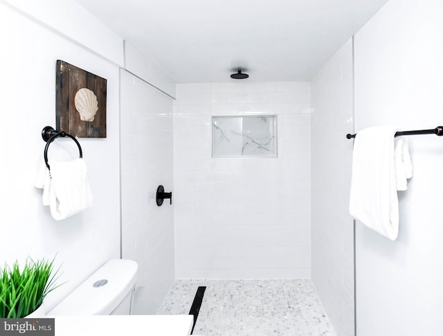 bathroom featuring a tile shower and toilet