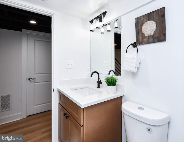 bathroom featuring toilet, vanity, and hardwood / wood-style floors