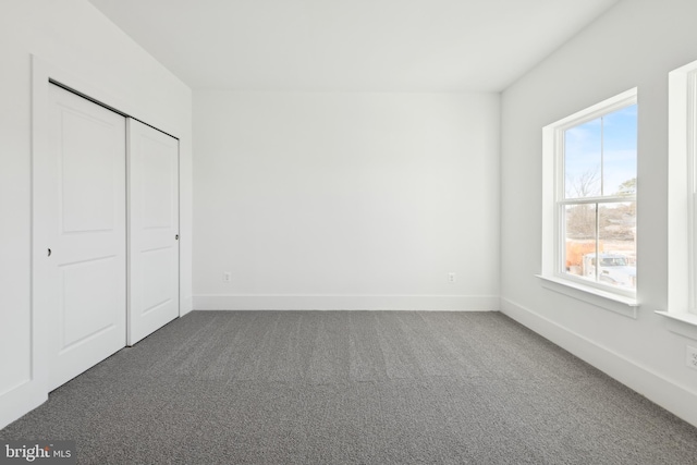 unfurnished bedroom with dark carpet and a closet