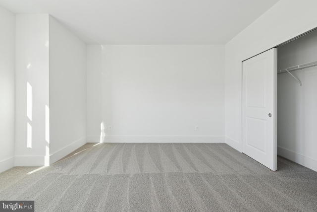 unfurnished bedroom with light carpet and a closet