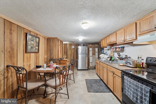 kitchen with stainless steel refrigerator, wood walls, black electric range, and sink