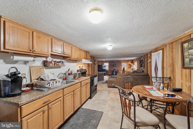 kitchen featuring sink, wood walls, black / electric stove, and a textured ceiling