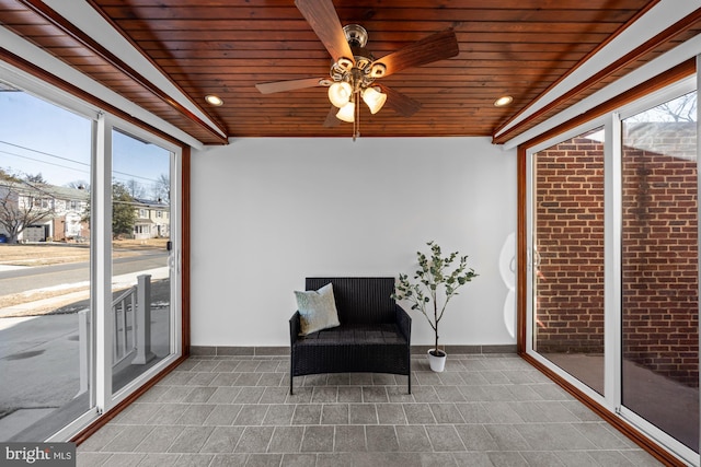 sunroom with ceiling fan and wooden ceiling