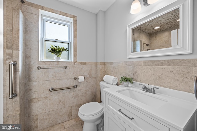 bathroom with vanity, tile patterned flooring, toilet, tile walls, and a tile shower