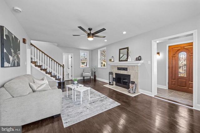 living room featuring hardwood / wood-style floors, ceiling fan, and a tiled fireplace