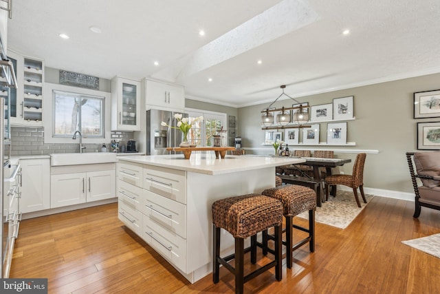 kitchen with a center island, sink, white cabinetry, a kitchen bar, and stainless steel fridge with ice dispenser