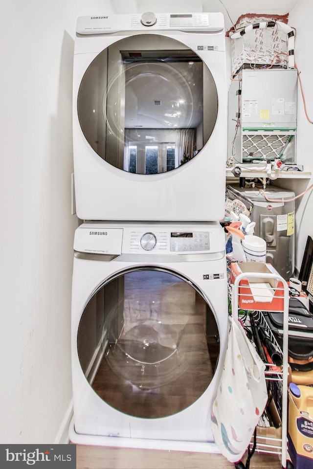 clothes washing area with stacked washing maching and dryer