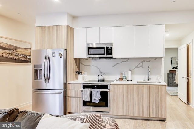 kitchen with white cabinets, stainless steel appliances, light hardwood / wood-style floors, and sink