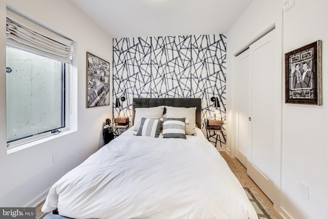 bedroom featuring light hardwood / wood-style floors, multiple windows, and a closet