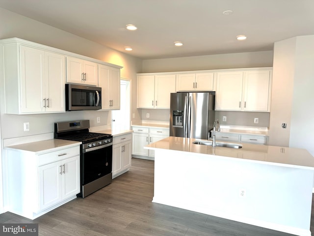 kitchen featuring appliances with stainless steel finishes, dark hardwood / wood-style flooring, a kitchen island with sink, sink, and white cabinets