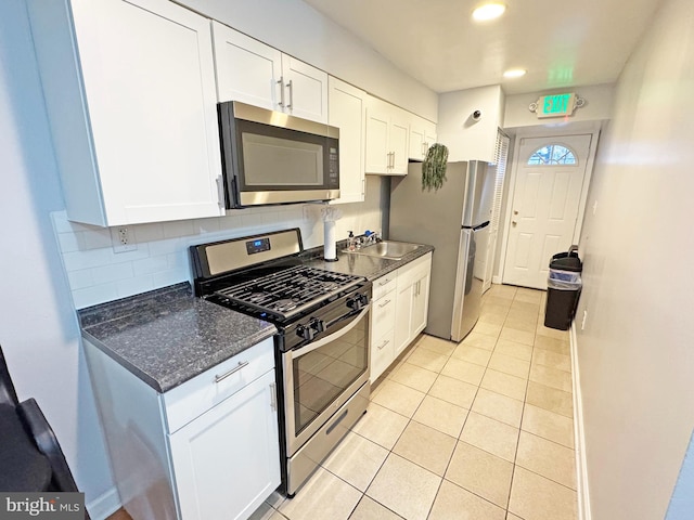 kitchen with backsplash, white cabinets, dark stone countertops, light tile patterned floors, and stainless steel appliances