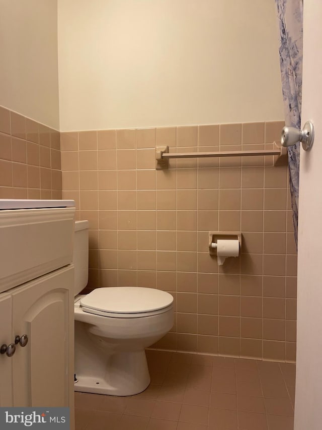 bathroom with tile patterned floors, vanity, tile walls, and toilet