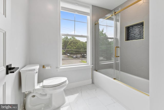 bathroom featuring toilet, bath / shower combo with glass door, and a healthy amount of sunlight