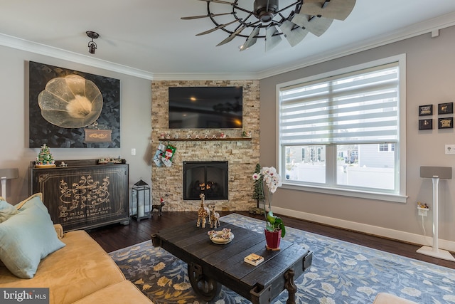 living room with ceiling fan, dark hardwood / wood-style floors, ornamental molding, and a stone fireplace