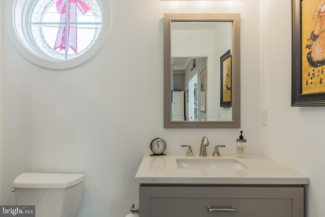 bathroom featuring toilet, vanity, and ornamental molding