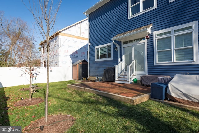 rear view of house featuring a storage unit and a lawn