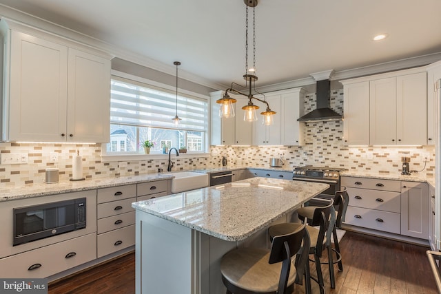 kitchen with a center island, white cabinets, black appliances, and wall chimney exhaust hood