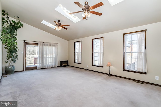 empty room featuring a skylight, carpet, visible vents, ceiling fan, and high vaulted ceiling