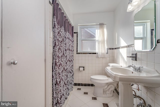 full bath featuring a wealth of natural light, tile patterned flooring, tile walls, and toilet