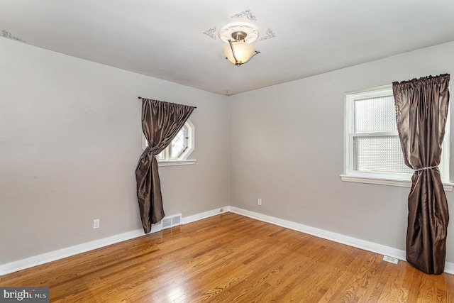 unfurnished room featuring visible vents, light wood-style flooring, and baseboards