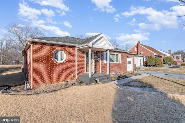 bungalow with a shingled roof, brick siding, driveway, and an attached garage