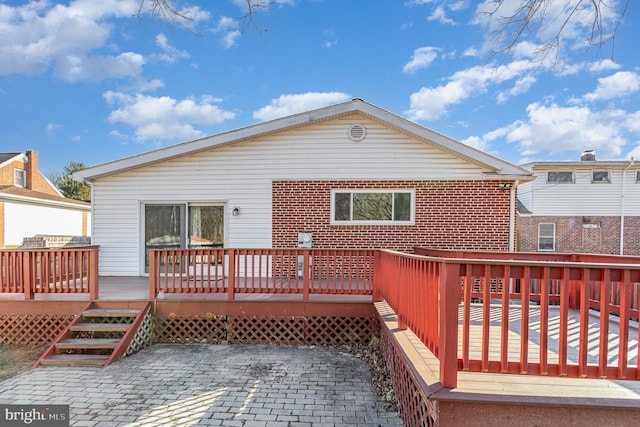 back of property featuring a patio, brick siding, and a wooden deck