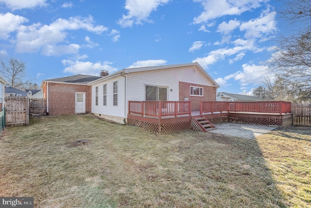 rear view of property with a fenced backyard, a lawn, brick siding, and a wooden deck