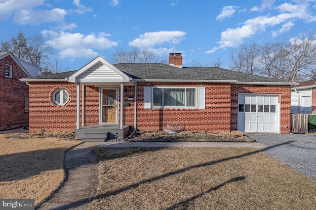 view of front of home with brick siding, a chimney, a shingled roof, an attached garage, and driveway