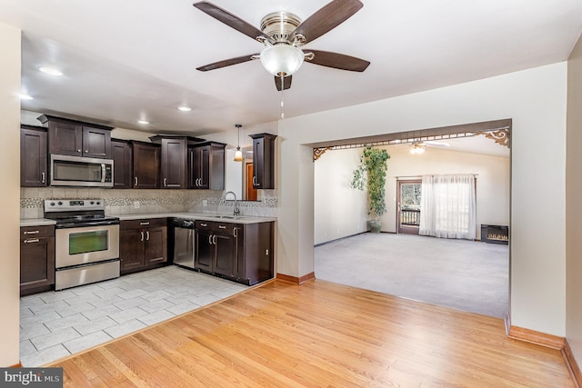 kitchen with stainless steel appliances, light countertops, dark brown cabinetry, and tasteful backsplash