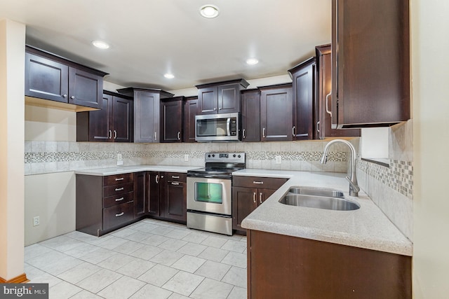 kitchen featuring dark brown cabinetry, decorative backsplash, stainless steel appliances, and a sink