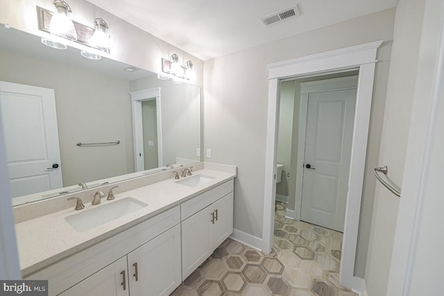 bathroom featuring visible vents, a sink, toilet, and double vanity