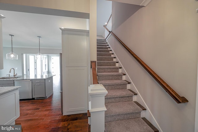 staircase with ornamental molding and wood finished floors