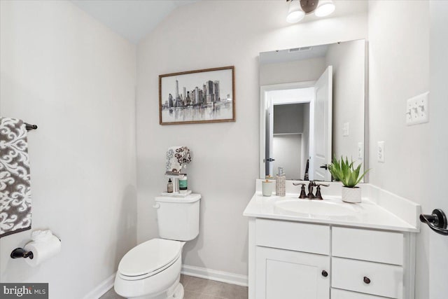 half bath with vanity, baseboards, vaulted ceiling, tile patterned flooring, and toilet
