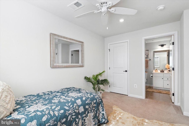 bedroom featuring ensuite bath, visible vents, carpet flooring, a sink, and baseboards