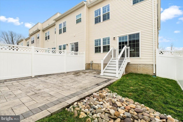 rear view of house featuring a fenced backyard and a patio