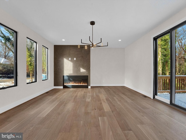 unfurnished dining area with a chandelier, a large fireplace, and light hardwood / wood-style floors