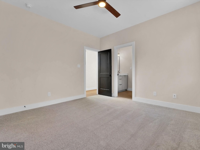 unfurnished bedroom featuring ceiling fan, light colored carpet, and ensuite bath