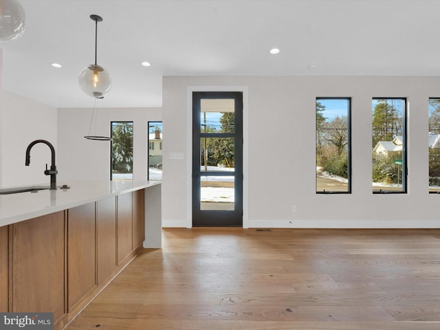 interior space featuring decorative light fixtures, plenty of natural light, light hardwood / wood-style flooring, and sink